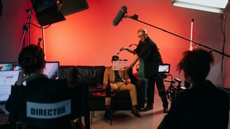 A director in a black shirt holds a clapperboard during filming