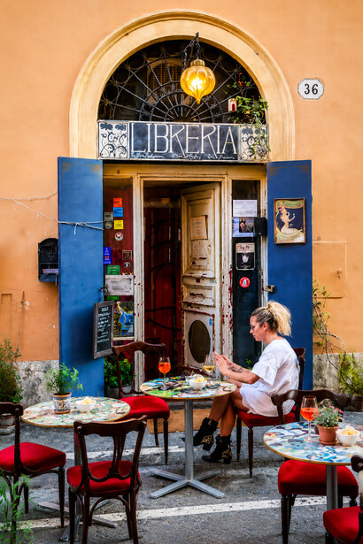 Young woman relaxing in a stylish bookstore tucked away in an alley of Rome’s Rione Monti district, Italy