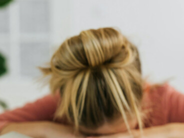 A girl sleeping with her head on open books, an image of fading energy and drift