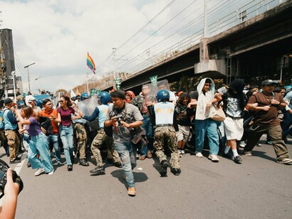 Crowds advancing toward a defensive line of riot police shields, embodying the intensity of anti-corruption demonstrations