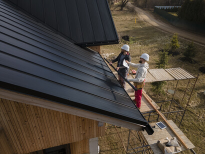 Roofers wearing helmets work on a portable housing structure