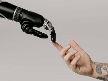A robotic hand touching the finger of a person, reflecting the emergence of AI as a reliable digital co-worker