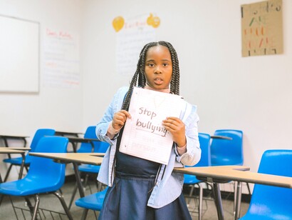 Aluna segura folha com o texto 'Pare o bullying'