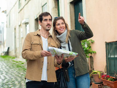 A man and woman walking along a street while looking at a map, Lisbon, Portugal