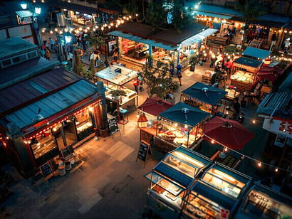 A lively night market illuminated by warm lights, symbolising the city’s culture of connection and everyday joy