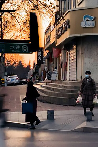 During sunset in China, people gather at a street corner, where the fading light meets the rhythm of the city