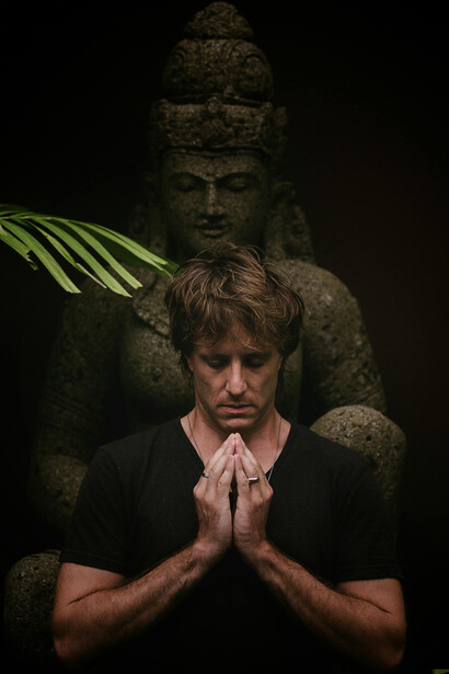 A moment of stillness beneath the gaze of an ancient stone figure, where introspection and silence meet in the shadows of the tropical night