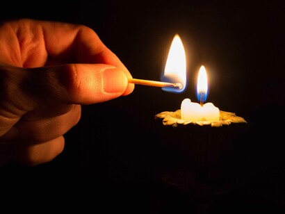 Pessoa acende uma vela com uma intenção de fé