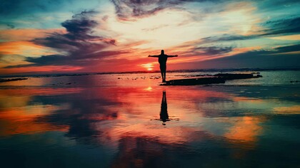 Channeling life with arms stretched out as the sun sets