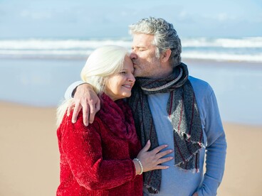 An elderly couple exercising together with a peaceful walk along the beach, embracing healthy aging