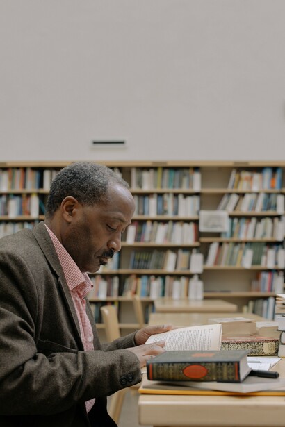 A man sat in a library reading a book. Understanding people can bring us closer to success