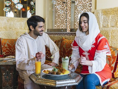Friends enjoying traditional cuisine surrounded by Moroccan architectural details, reflecting the role of cultural experiences in shaping perceptions of a country