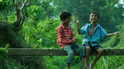 Two children sitting on a fence talking