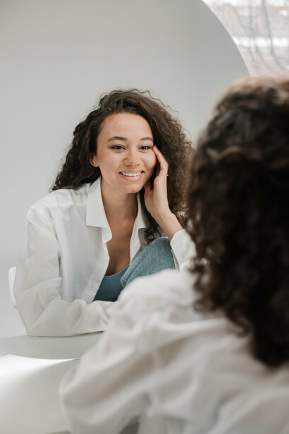 Woman smiling as she watches herself in mirror