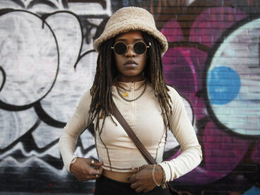 A woman standing in front of a graffiti wall, yet part of a larger story of generational awakening