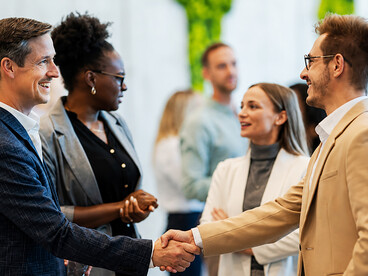 Diplomats and business leaders shaking hands during an international conference, symbolizing cooperation, negotiation, and global partnerships