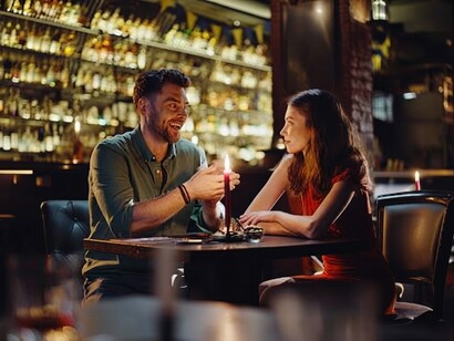 A happy young couple shares a lively conversation during an evening date at a modern pub