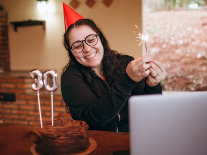 A woman celebrating her 30th birthday online on her laptop, feeling happy and embracing the independence and freedom that come with this milestone
