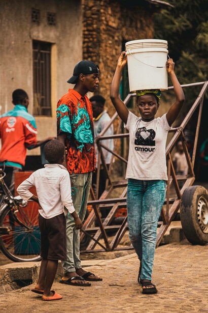 Young teen with a white bucket walks through the neighbourhood