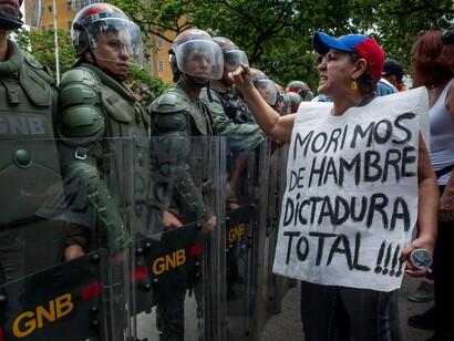 Un hombre luce una pancarta de protesta ante un grupo de soldados