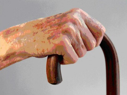 Una mano anciana agarrada a un bastón 