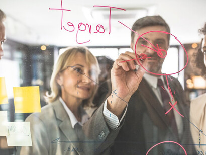 Executives mapping out goals and action plans on a glass wall, emphasizing career planning and pathways to professional growth