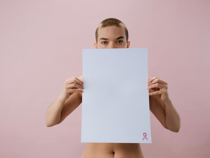 Woman holding a white paper with the Pink Ribbon, symbol of breast cancer awareness