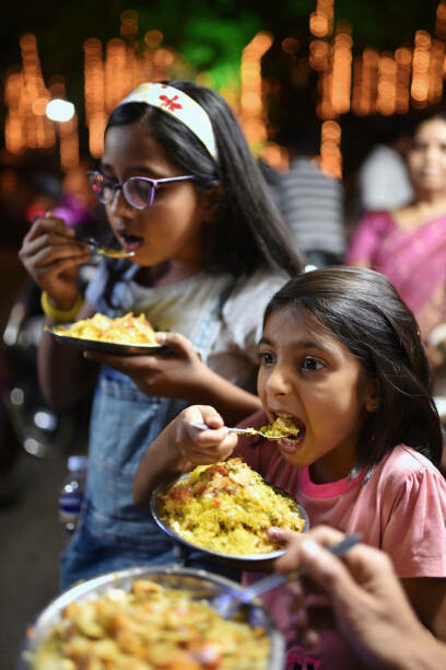 Family gathered at night, enjoying street food, with girls in Mumbai sampling local delicacies