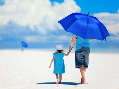 Un padre paseando por la playa con su hija