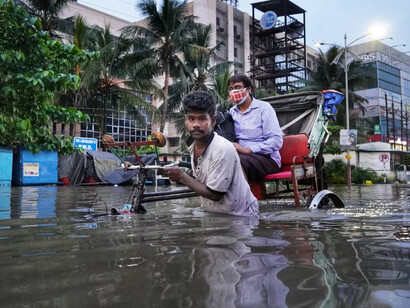 Two men standing in a flooded street next to a bike
