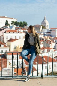 
A woman sitting on metal railings and watching the scenery in Lisbon, Portugal