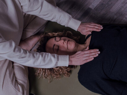 The practitioner’s hands hover gently above the recipient, symbolising the delicate art of Reiki and its focus on promoting physical and emotional healing