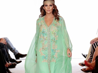 A model wearing a green caftan exhibiting the work of fashion designer Albert Oiknine