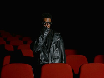 Homem jaqueta de couro preta em pé atrás da cadeira vermelha do teatro