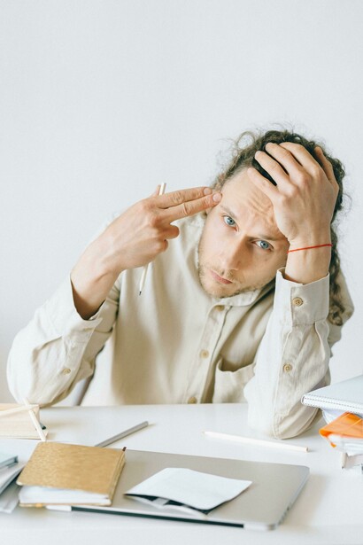 A man in a white shirt working at a table, showing signs of burnout