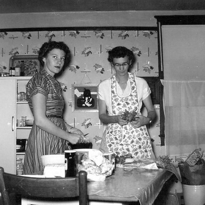 Two women bonding in the kitchen, capturing the essence of family togetherness and culinary tradition in the 1950s