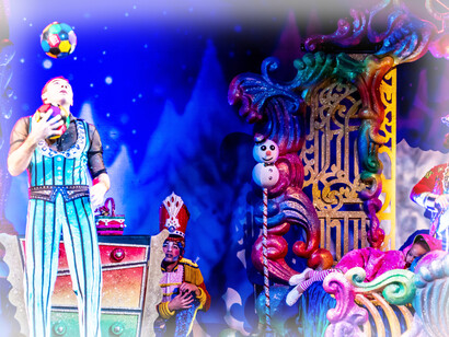 A juggler begins his act on a colorful stage with many props nearby to look like a fantasy world