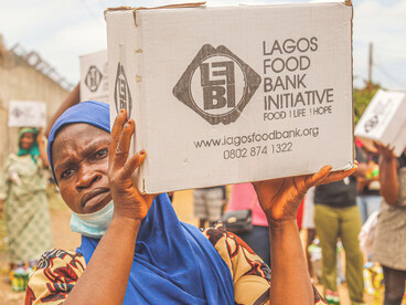 A group of women carrying cardboard boxes on their heads wait in a food aid distribution line during the hunger crisis in Lagos, Nigeria