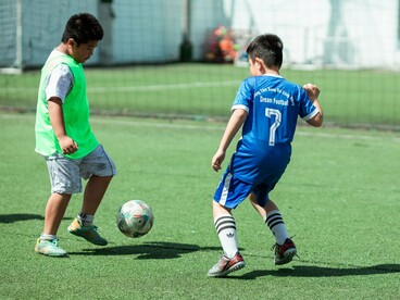 Two young footballers battling for possession, symbolising the competitive spirit that drives continual improvement