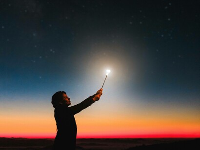 A woman holding a wand that is lighting her path