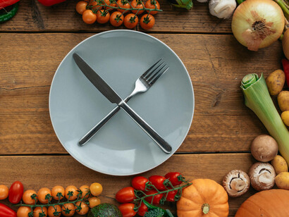 Plate with fork and knife crossed in front of vegetables, shows harmony and balance through diets like raw vegan