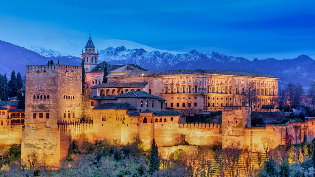 At dawn, the Alhambra Palace in Granada, Spain, stands gracefully near the snow-capped Sierra Nevada mountains, Spain