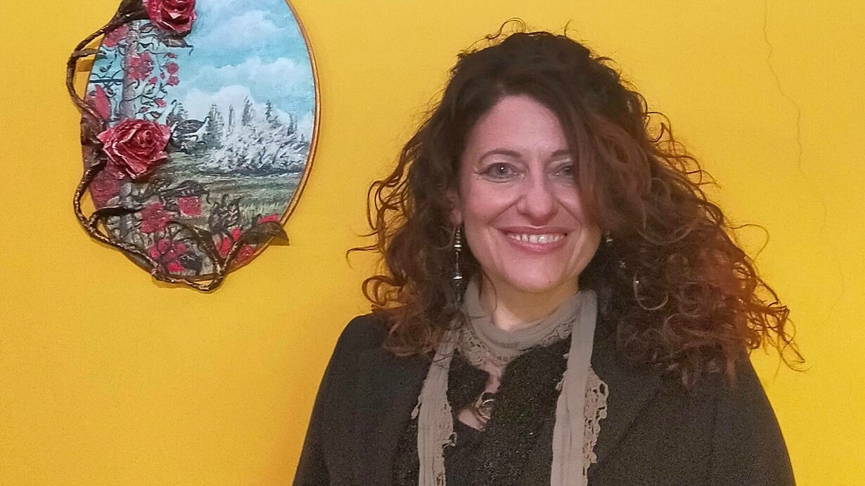 Nora Art next to one of her painted pieces