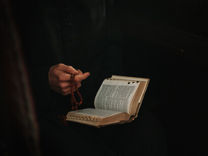 Sacerdote rezando el rosario con la biblia en mano