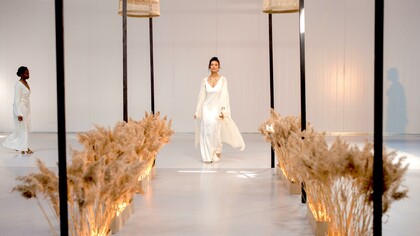 Uma modelo usando um vestido branco andando na passarela