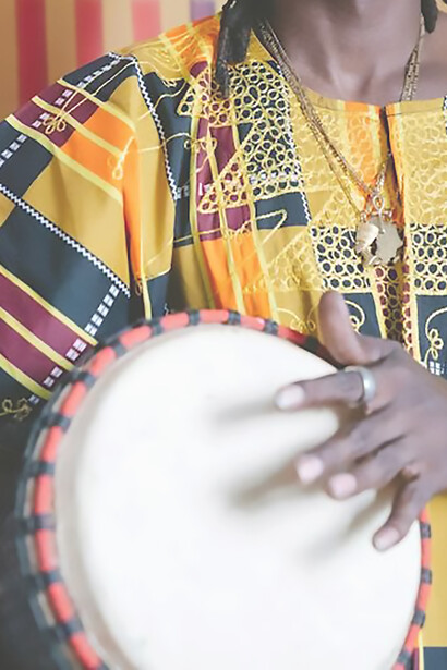 In vibrant traditional attire, an African man skillfully plays an instrument, immersing himself in the rhythmic heritage of his culture