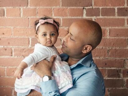 The godfather holding an adorable goddaughter who's looking on straight at the camera
