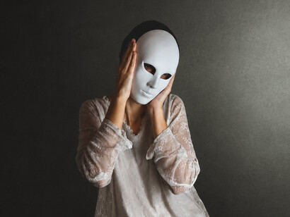 As a woman lifts one mask away, another remains underneath, representing the hidden self concealed beneath social roles, expectations, and appearances