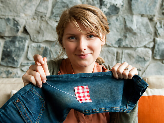Woman repairing a pair of jeans using traditional visible mending techniques