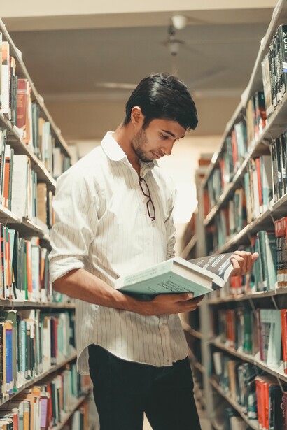 A man looking a books in a library. Greeks almost said that deception lives in truth